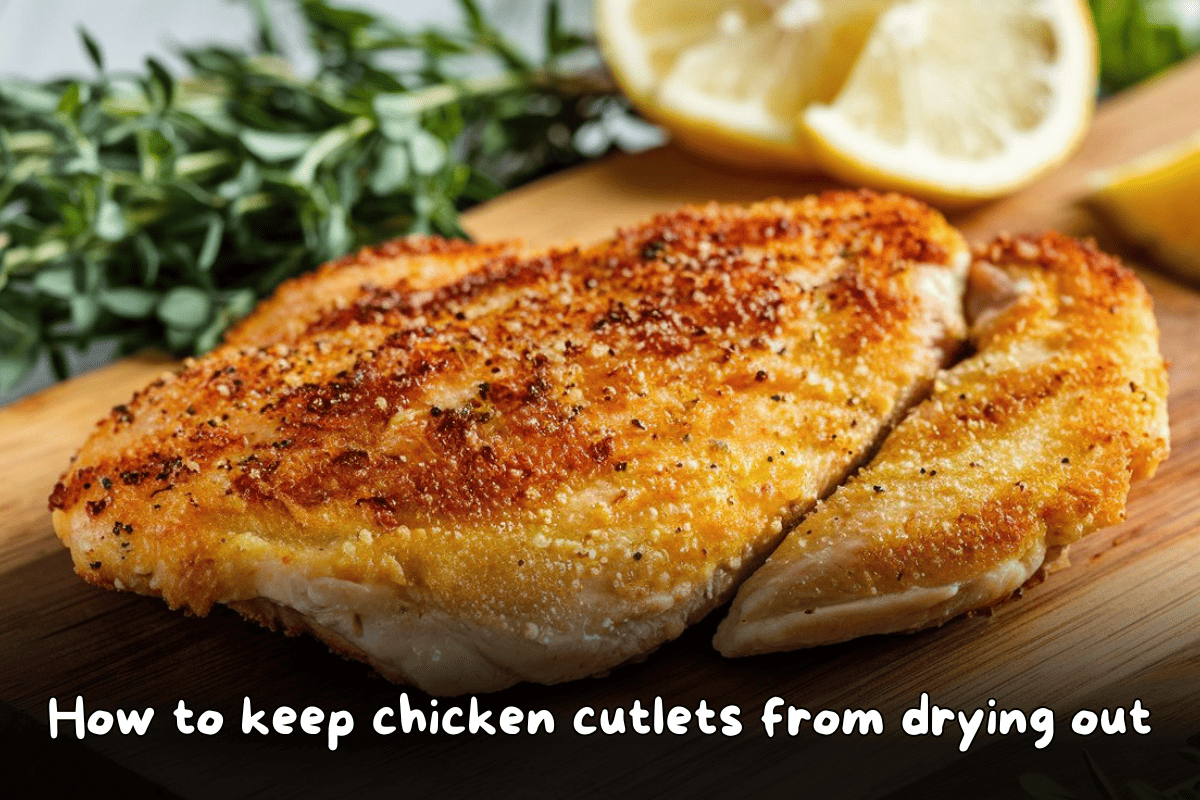 Golden-brown chicken cutlet served with lemon slices and herbs on a wooden cutting board."