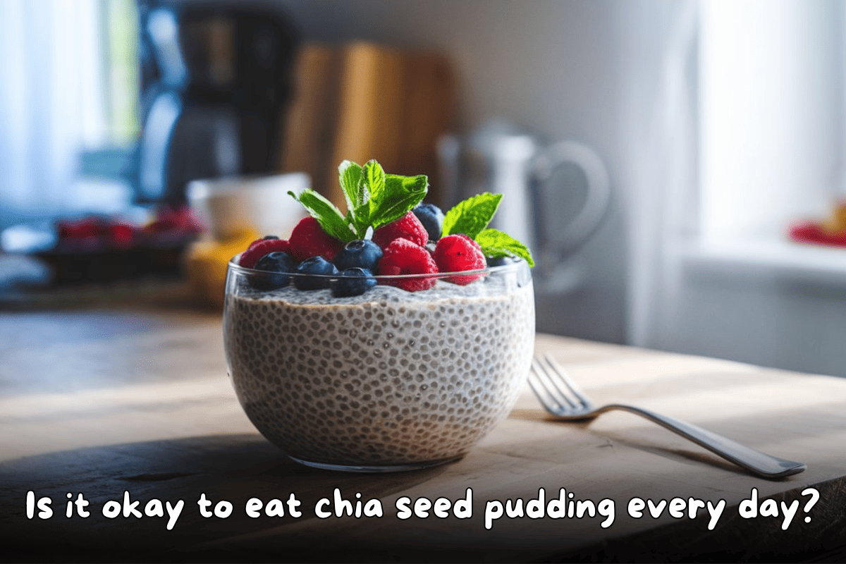 A glass bowl of chia seed pudding topped with fresh blueberries, raspberries, and mint leaves, placed on a wooden table with natural light in the background.