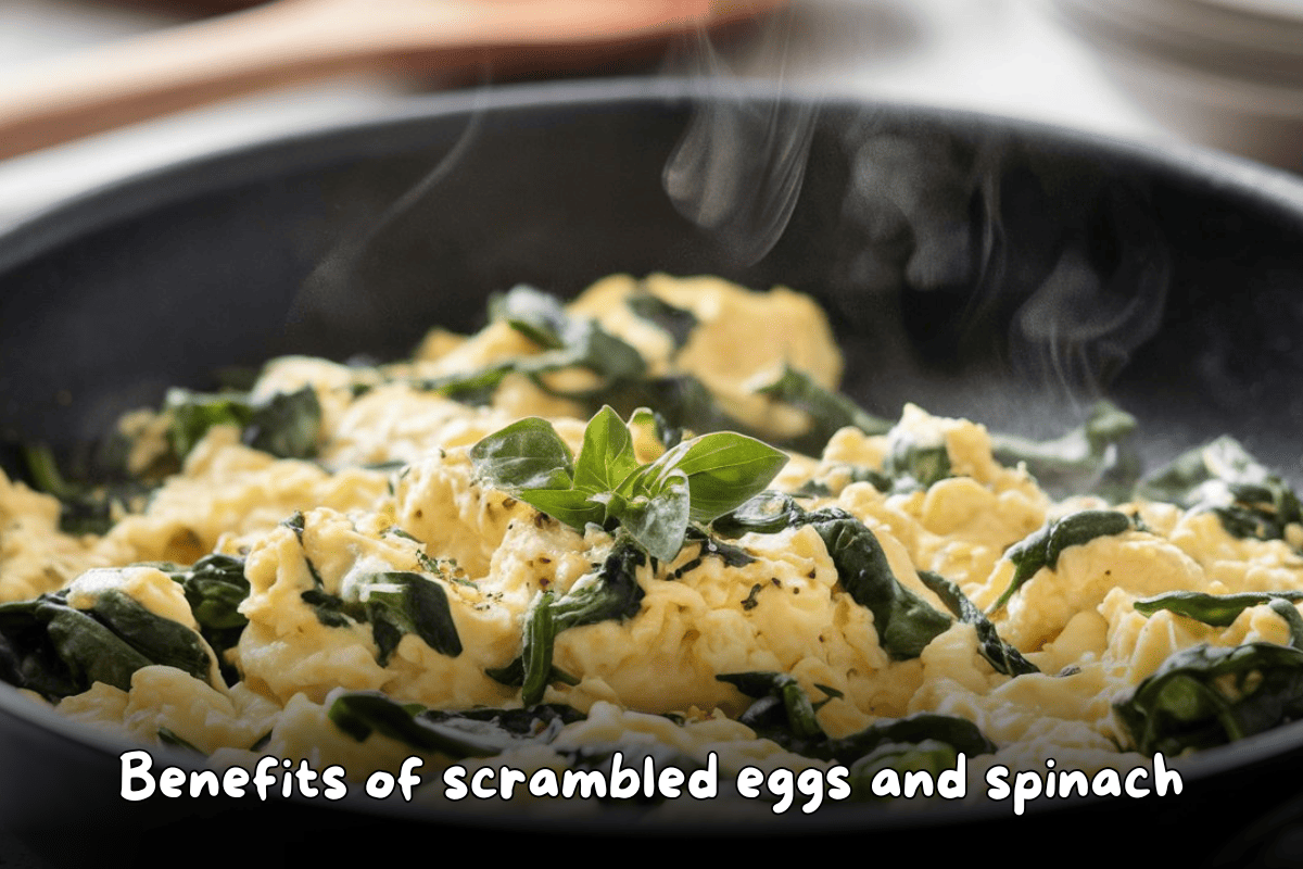 Scrambled eggs with spinach steaming in a pan, garnished with fresh basil leaves.