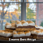 Close-up of gooey S'mores Bars with toasted marshmallows, chocolate, and graham cracker crust on a plate.